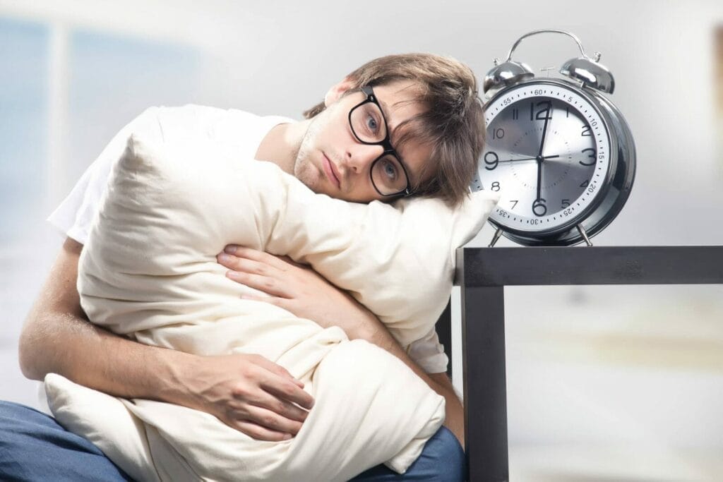 a man hugging pillow with his head resting on the table
