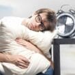 a man hugging pillow with his head resting on the table