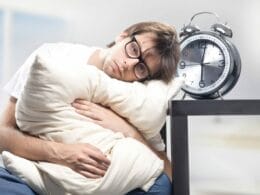 a man hugging pillow with his head resting on the table